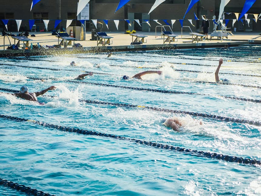 instructor exponiendo su clase de nado a los alumnos en la alberca semi olimpica